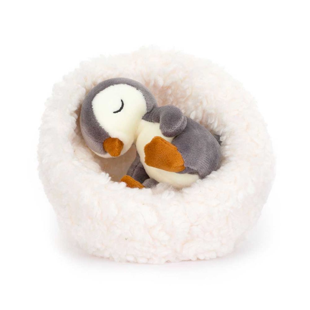 Jellycat Sovende pingvin i rede. Den grå og hvide pingvinunge ligger i en blød pude af plys.