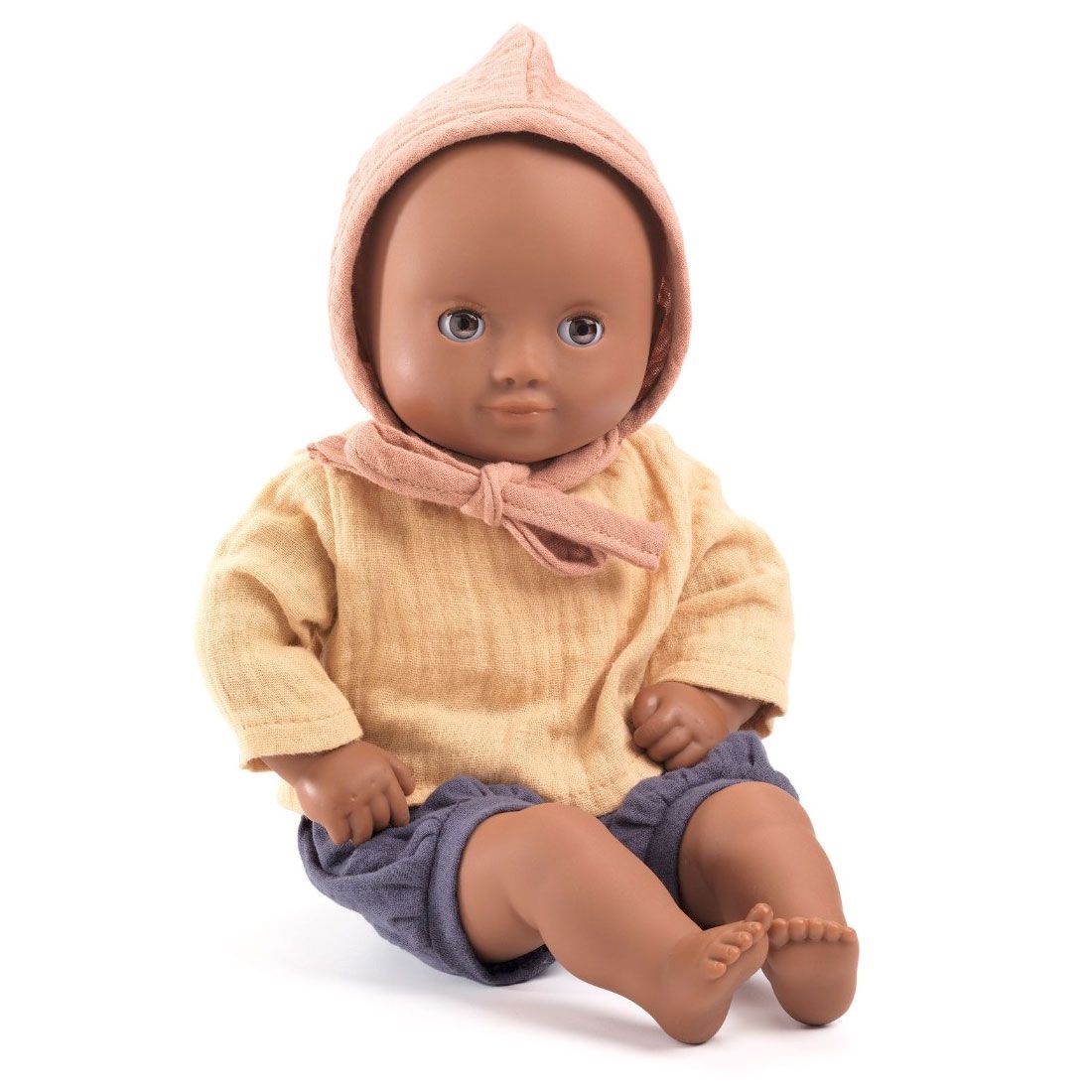 Babydukke med brune øjne og hudfarve fra Djeco. Dukken har bukser, skjorte og kyse på.